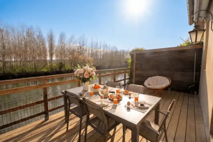 Grande terrasse au bord de l'eau du gîte en Dordogne